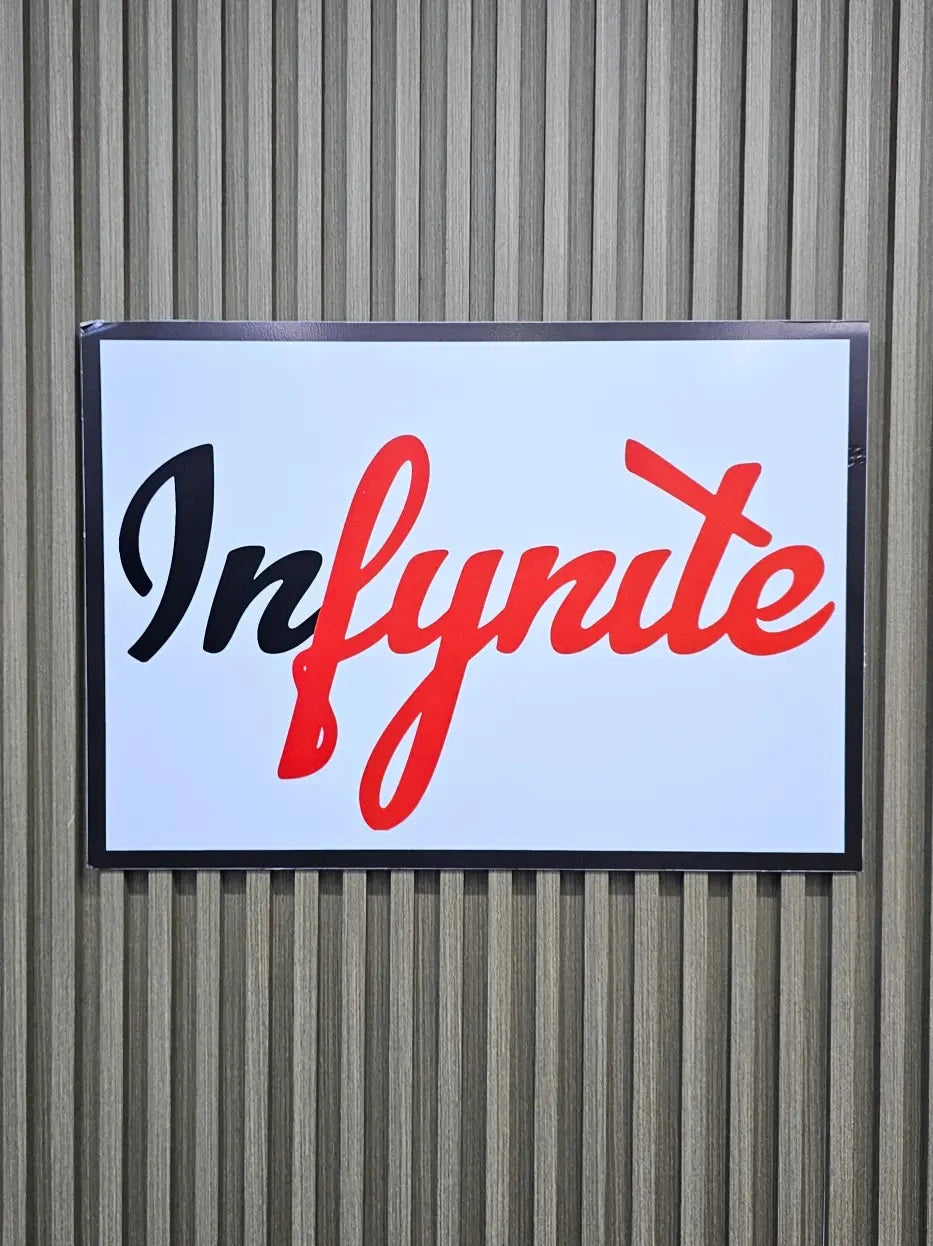 Infynite logo on a rectangular sign with a white background against a corrugated metal wall.