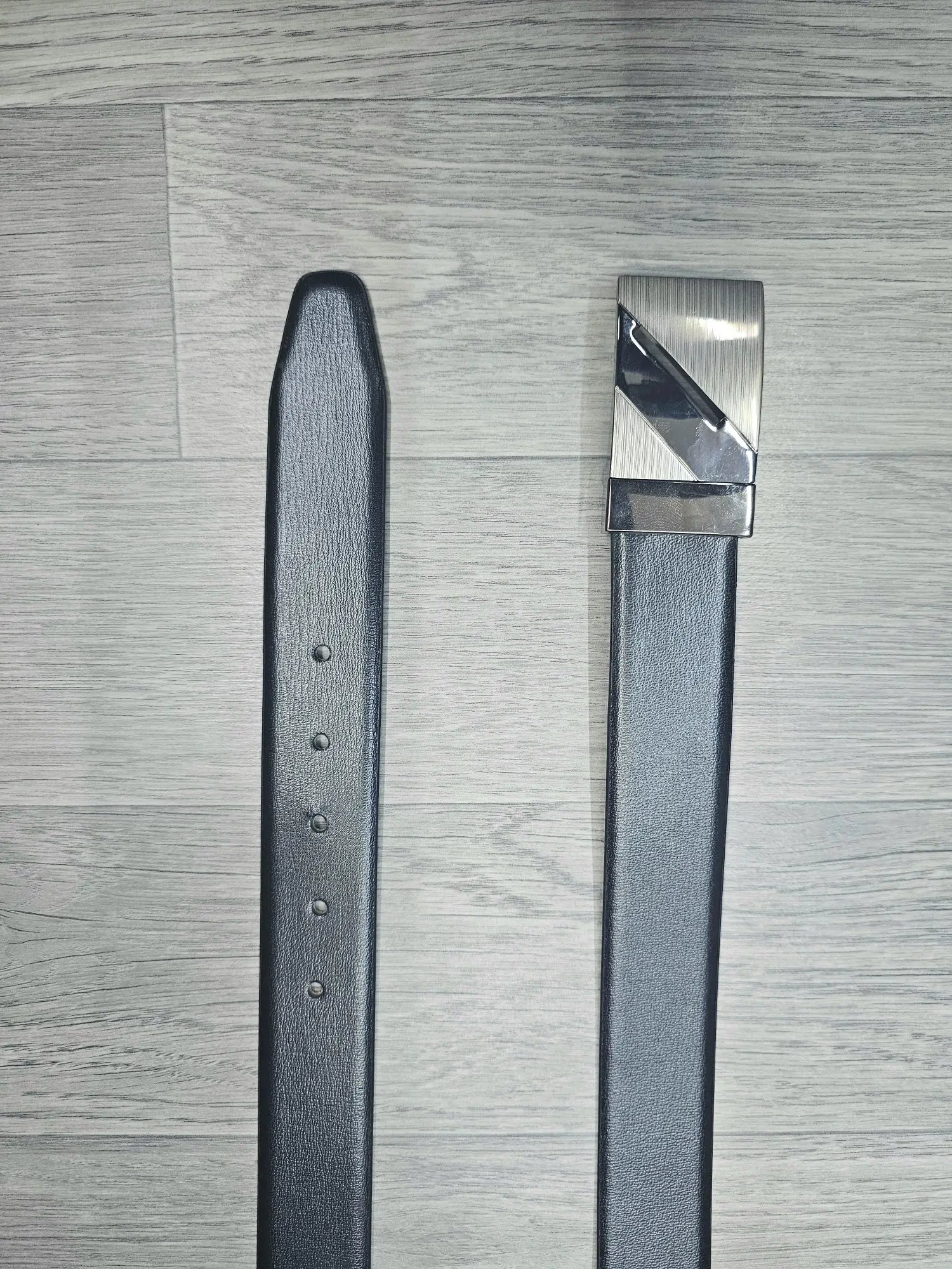 Gray belt with a silver buckle on a wooden surface