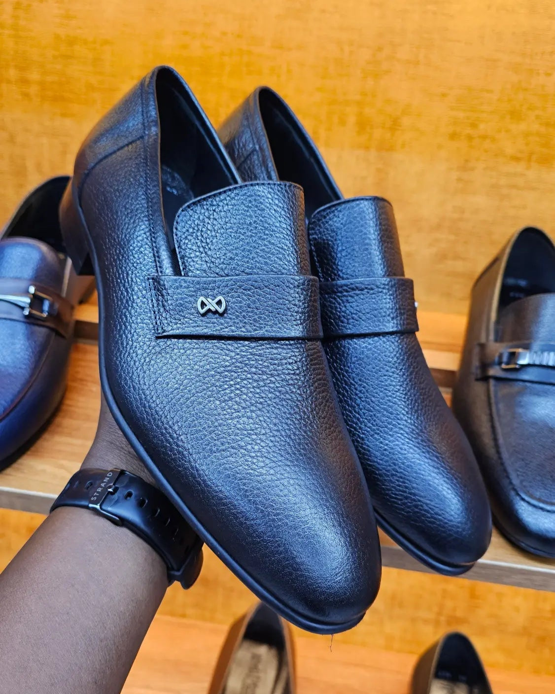 Black leather loafers on a wooden surface