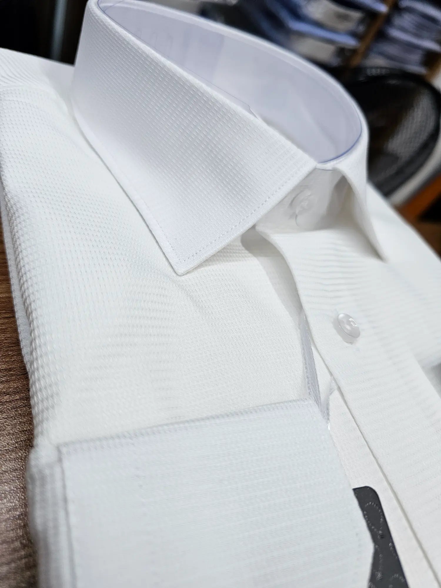 Close-up of a white dress shirt with a textured collar and cuffs.