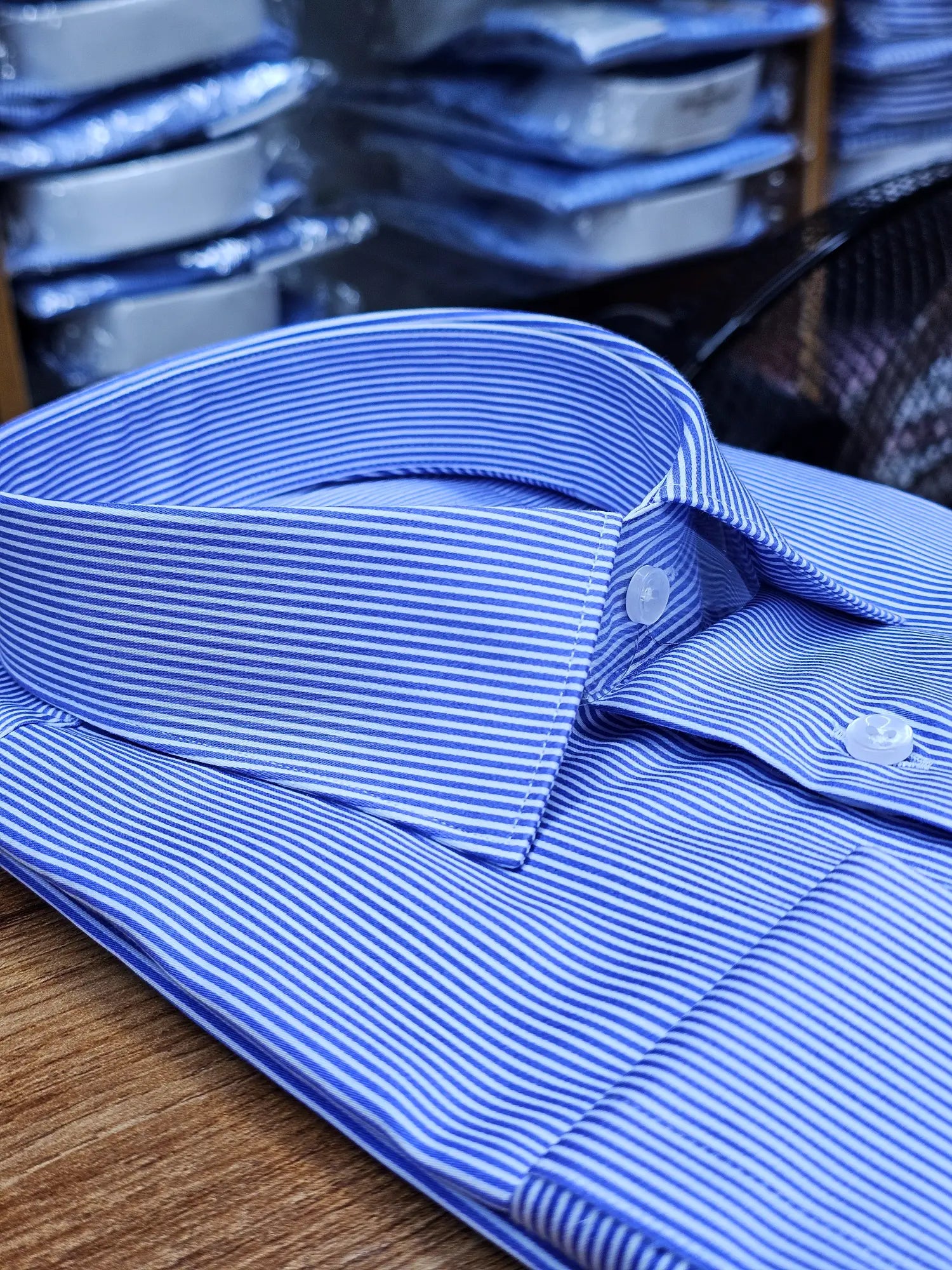 Blue striped shirt on a wooden surface with blurred background