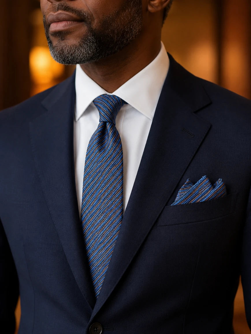 Infynite denim blue multi-colour micro diagonal stripe tie and pocket square set styled with a navy suit and white dress shirt