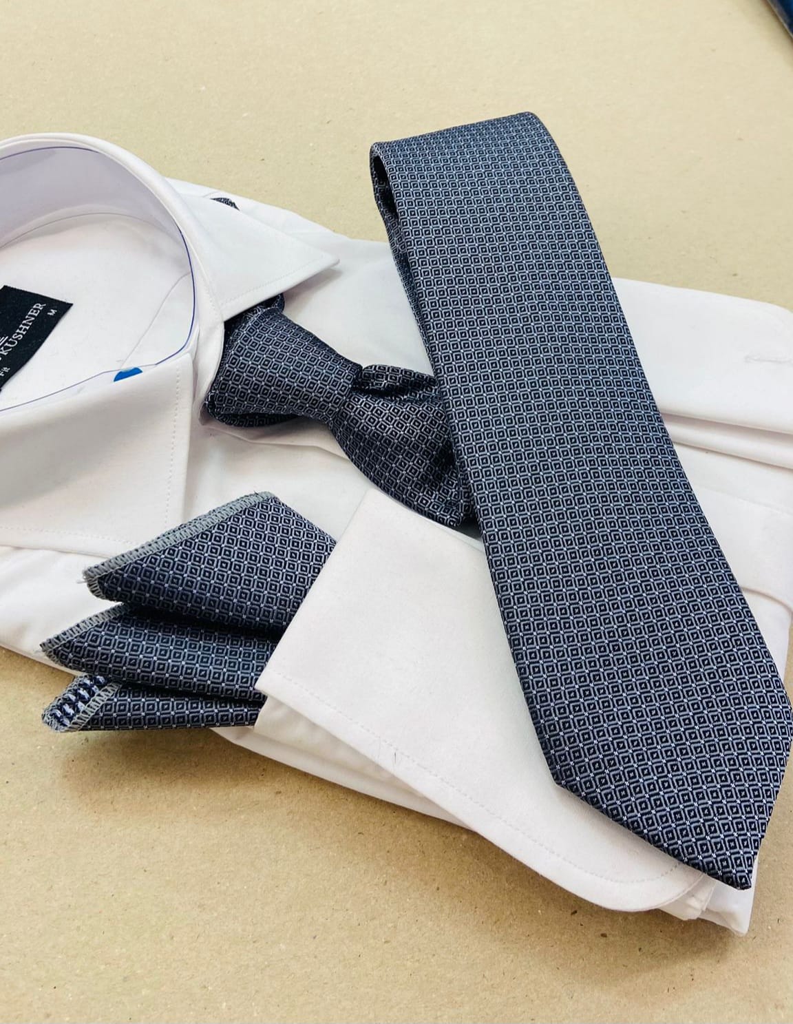 Blue patterned tie and pocket square on a white shirt with a beige background