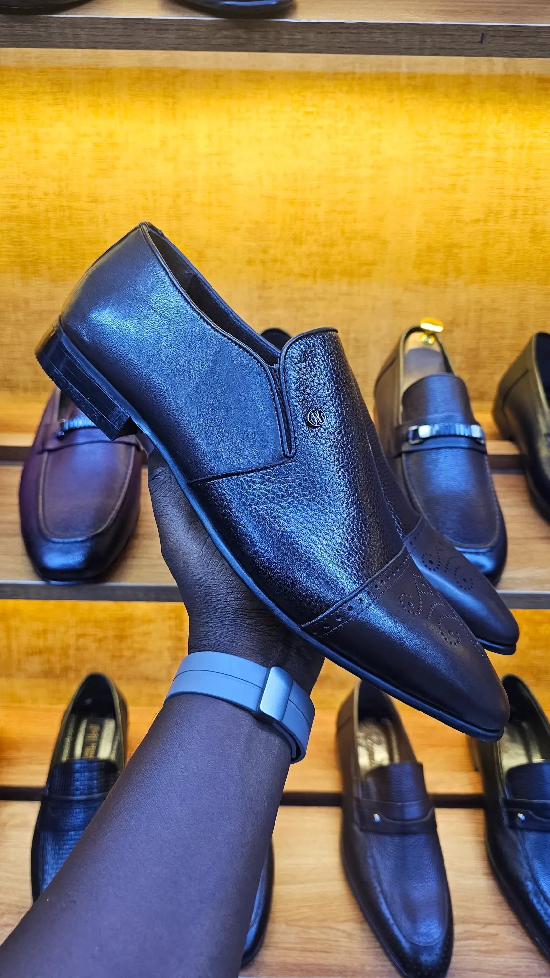 Black leather shoes on a wooden surface with other shoes in the background