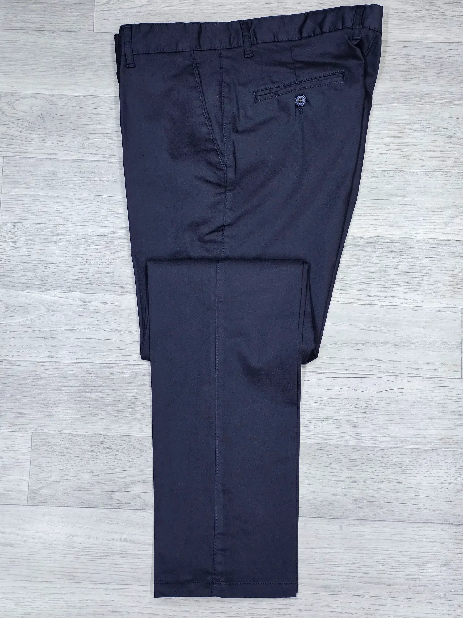 Navy blue regular fit chino pants on a light gray wooden floor