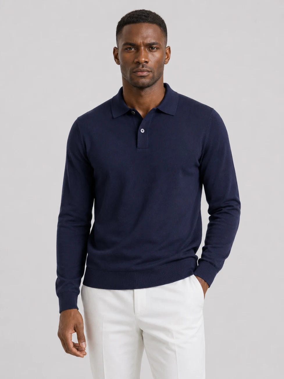 African man wearing an Infynite navy blue long-sleeve knitted polo sweater with off-white trousers.