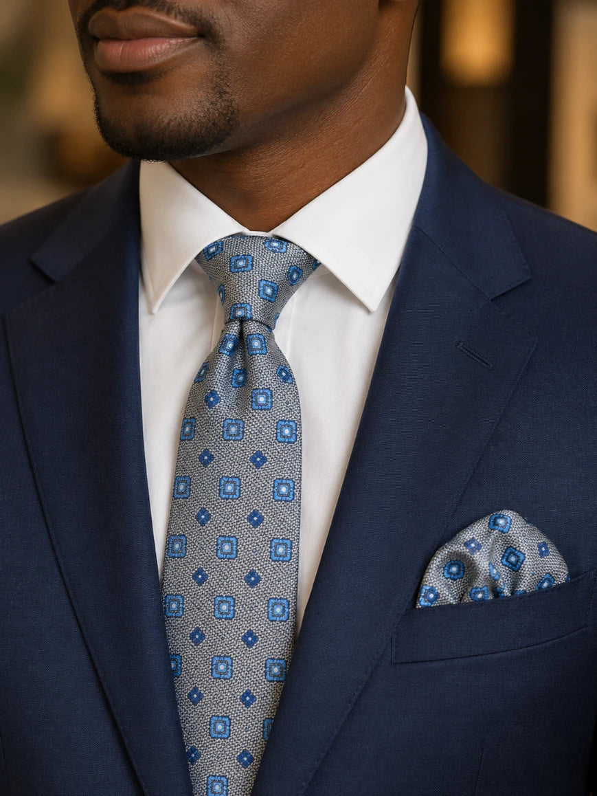 Infynite silver grey and blue geometric square medallion tie and pocket square set styled with a navy suit and white dress shirt