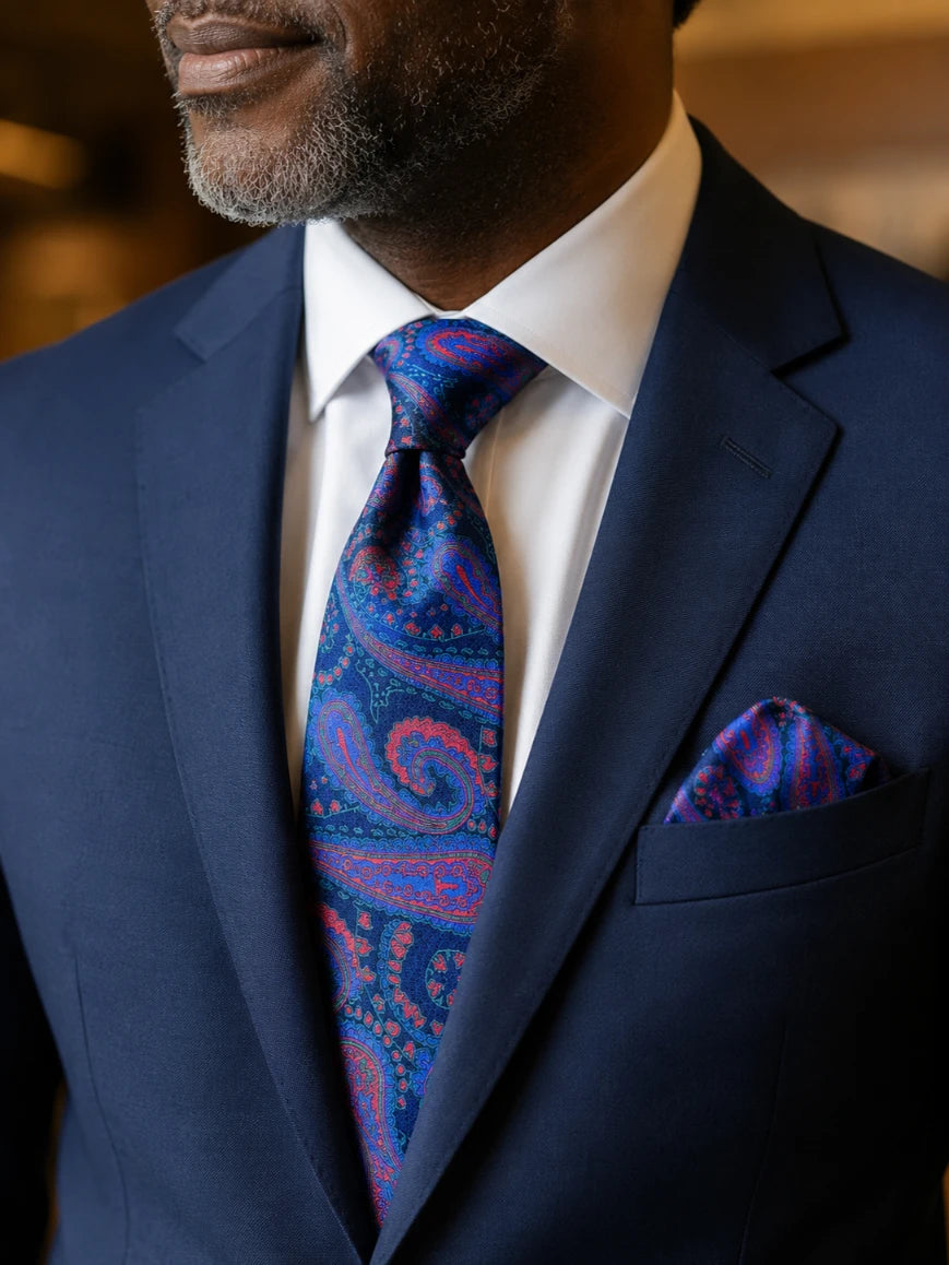 Infynite royal blue and crimson red large-scale paisley jacquard tie and pocket square set styled with a navy suit and white dress shirt