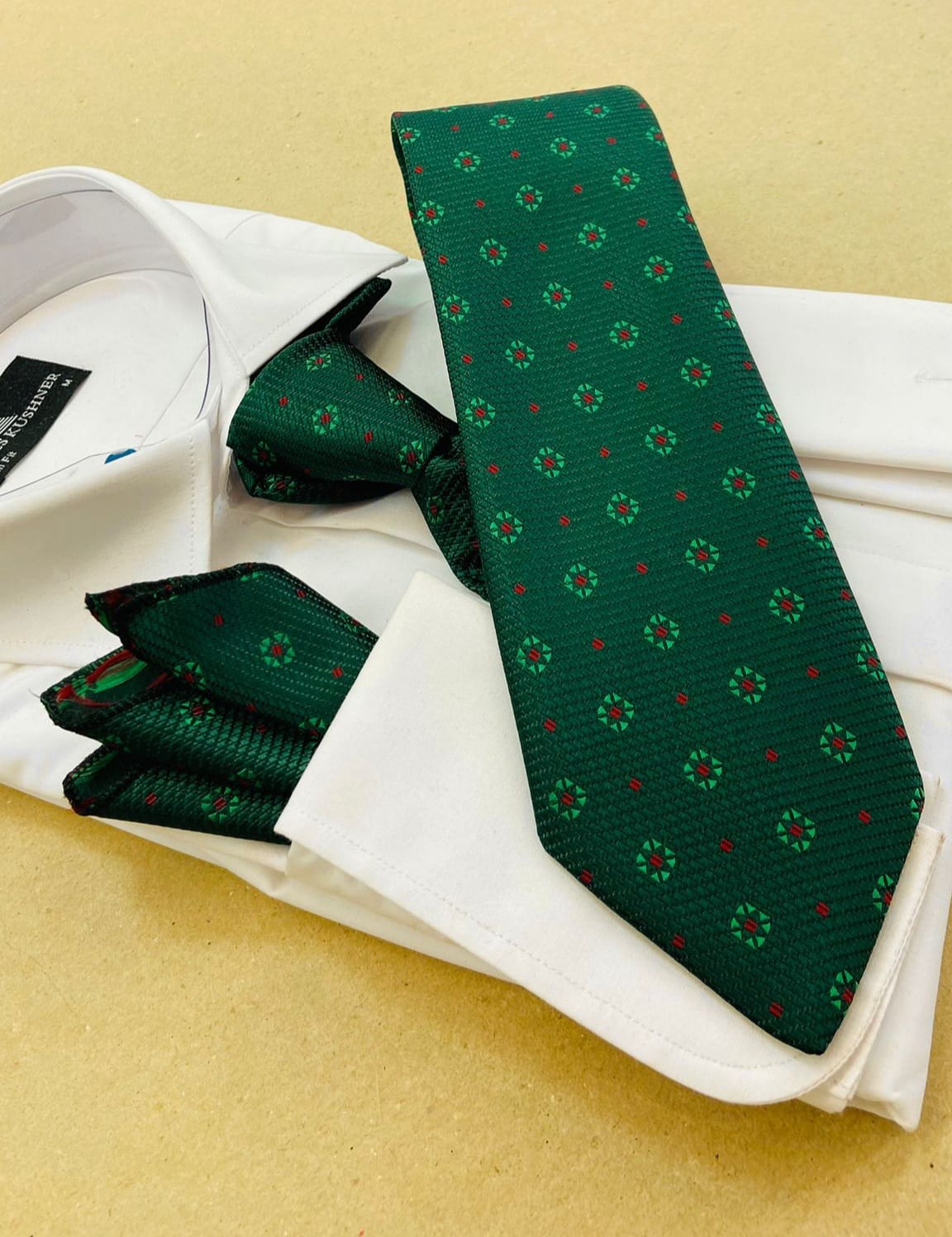 Green patterned tie and pocket square on a white shirt with a beige background