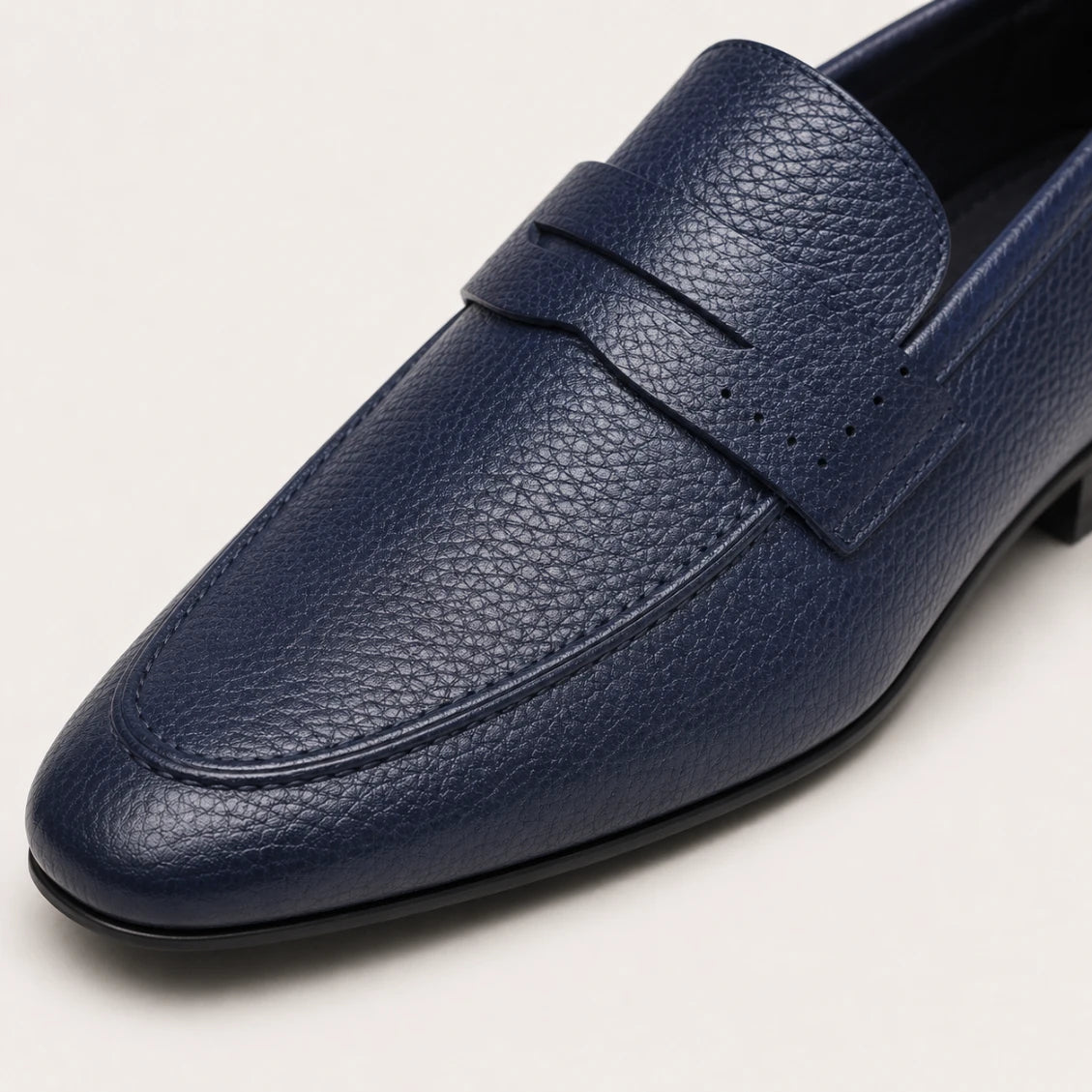 Blue leather loafer shoe on a light gray background