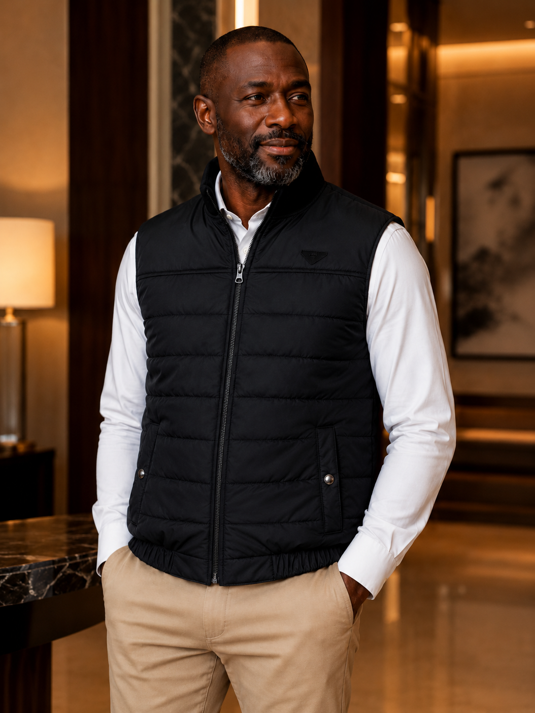 Man wearing a black puffer vest over a white shirt in an indoor setting