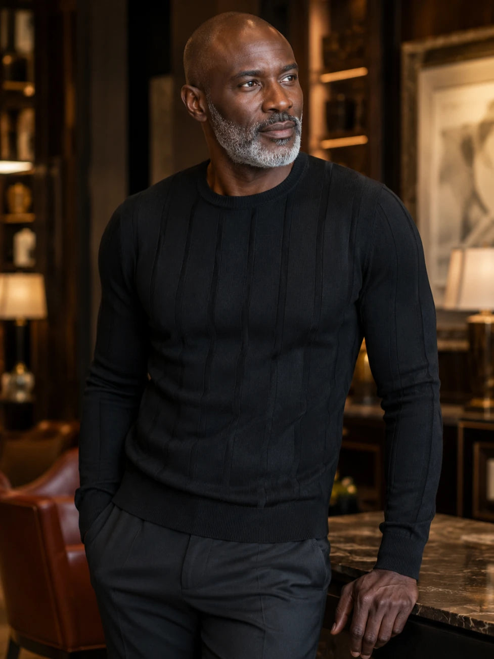 Man wearing a black sweater in an indoor setting with warm lighting