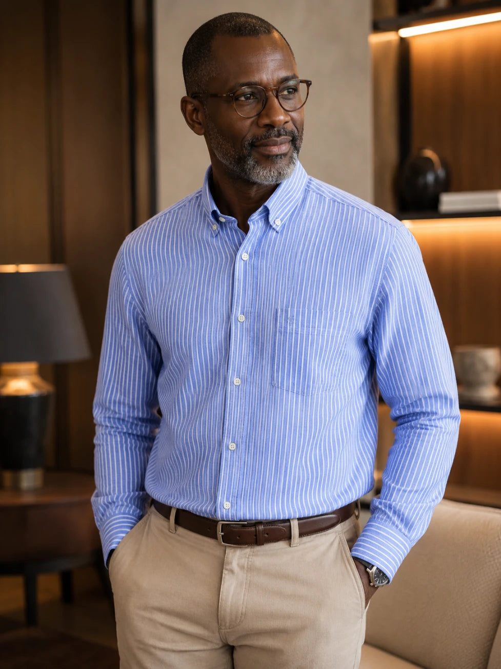 Man wearing a blue striped shirt and beige pants in an indoor setting