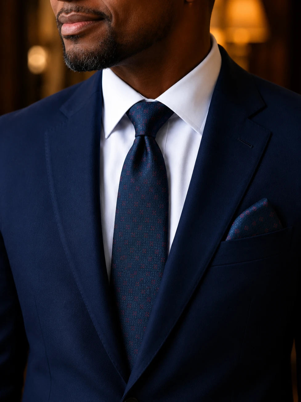 Man wearing a navy suit with a white shirt and dark tie.