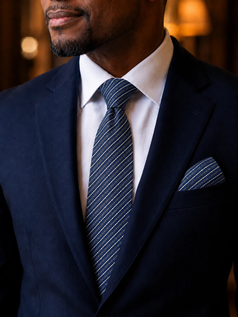 Man wearing a navy suit with a white shirt and striped tie.
