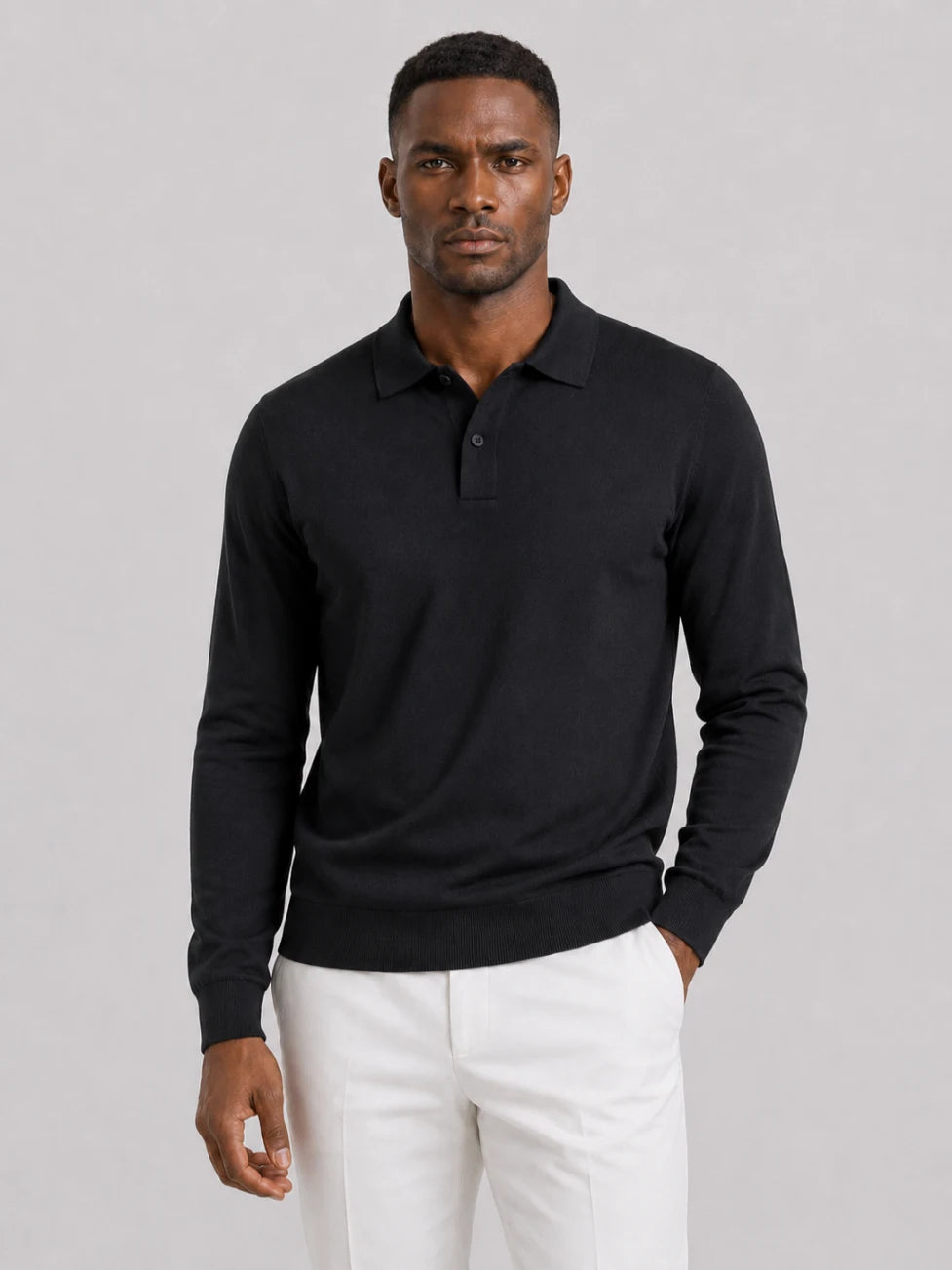 African man wearing an Infynite black long-sleeve knitted polo sweater with off-white trousers.