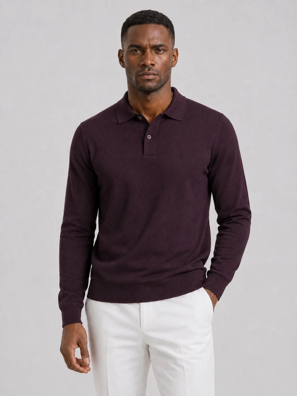 African man wearing an Infynite burgundy long-sleeve knitted polo sweater with off-white trousers.