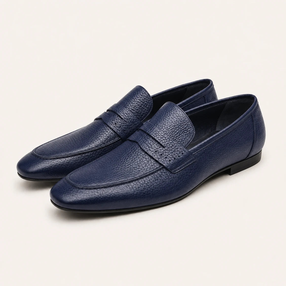 Pair of blue leather loafers on a light beige background